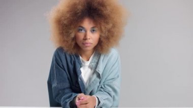 Stüdyoda uzun afro saçlı, melez bir zenci kadın yavaş çekimde uzaklaşır.