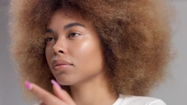 Misto raça negra mulher com grande afro cabelo no estúdio colocar uma mancha creme — Vídeo de Stock