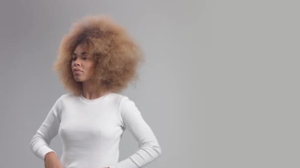 Panned porträtt blandras kvinna vänder sig till kameran och vidrör hennes afro hår — Stockvideo