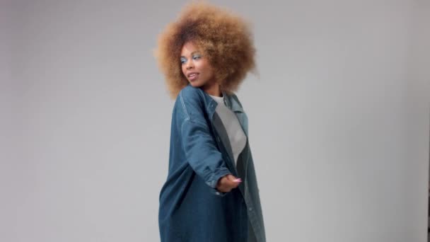 Змішана раса чорна жінка з афро волоссям в студії поодинці в джинсовій сорочці повільний рух — стокове відео