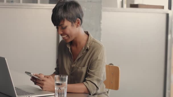 Mujer de raza mixta negro delante de cuaderno abierto procrastina con teléfono inteligente — Vídeo de stock