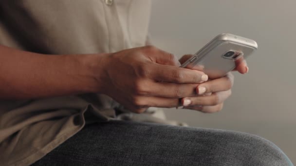 Primer plano de las manos de la mujer de raza mixta mensajes de texto en el teléfono inteligente y luego inclinarse para hacer su retrato — Vídeo de stock