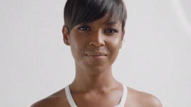 Melez ırk siyahi kadın stüdyoda kameraya bakıyor ve gülümsüyor.