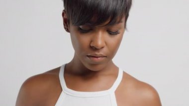 Karışık ırk siyahi kadın aşağı bakıyor ve sonra kameraya dönüp saçına dokunuyor.