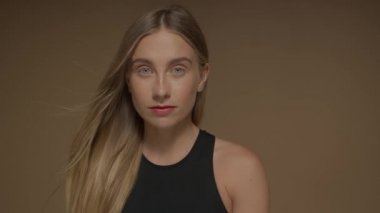 Stüdyoda mavi gözlü ve uzun sarı saçlı genç bir kadın. Yakın plan portre