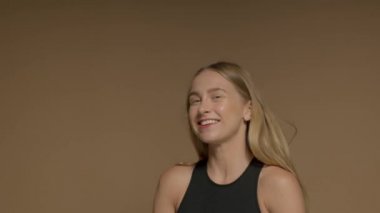 Eğlenceli, mutlu, genç bir kız kameraya döner ve saçlarını savurur.