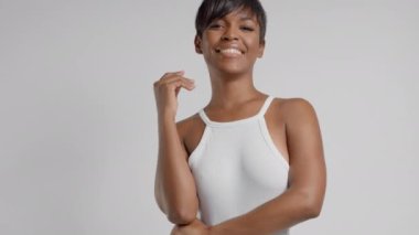 Stüdyoda kısa saç kesimi ve yumuşak tenli, gülümseyen melez bir kadın.