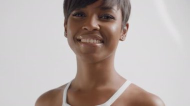 Melez ırk siyahi kadın stüdyoda kameraya bakıyor ve gülümsüyor. 