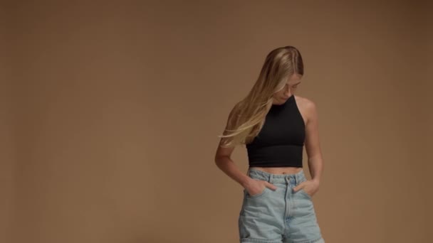 Mujer rubia con pelo largo en estudio sobre fondo beige cálido — Vídeo de stock