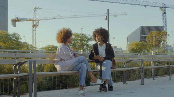 Un par de mujeres negras de raza mixta en el parque sentadas y hablando —  Fotos de Stock