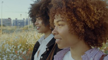 Yakın plan, iki melez ırkın portresi. Parkta yürüyen ve ileriye bakan siyahi kadın.