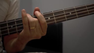 İnsan elinin, bas gitar ve akort iğneleriyle çaldığı yakın plan.