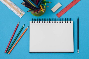 Boş spiral defter ile beyaz sayfa ve mavi bir tabloda çok renkli ileti örneği. Çalışma alanı renkli arka plan üstünde not etmek ile. Eskiz defteri giriş metni, en iyi görünüm için. Geri okul kavramı.