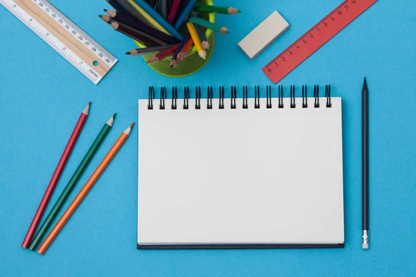 Boş spiral defter ile beyaz sayfa ve mavi bir tabloda çok renkli ileti örneği. Çalışma alanı renkli arka plan üstünde not etmek ile. Eskiz defteri giriş metni, en iyi görünüm için. Geri okul kavramı.