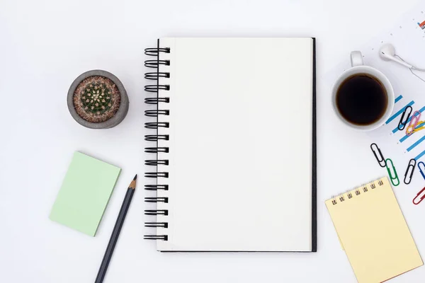 Office desk table with blank notepad page, pencil,cactus, coffee cup and supplies. Workplace with notebook on white background. Minimal business concept. Free space for input text. Top view.