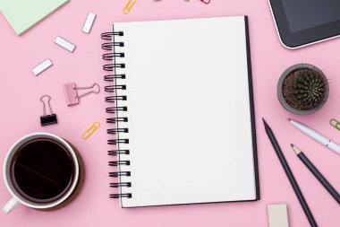 Üstten görünüm çalışma alanı mockup defter, kaktüs, kalem, kurşun kalem, fincan kahve, klipler ve aksesuarları ile pembe arka plan üzerinde. Mockup