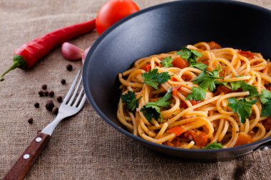 Domatesli İtalyan makarnası ve keten masa örtüsünde maydanoz.