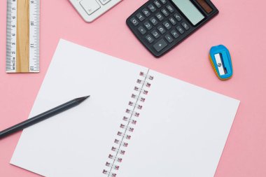 Üst görünüm boş spiral defter ve pembe pastel arka planda yer alan kalem. Fikirler için boş yazı defteri ve renkli arkaplanda ilham