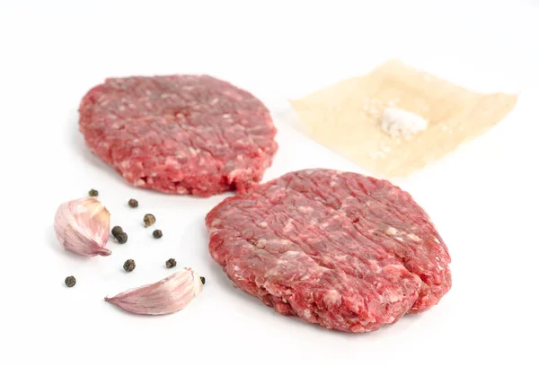 uncooked hamburgers and other ingredients isolated on white