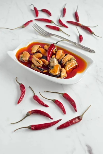 red chili peppers and mussels tray with silver fork on marble ba