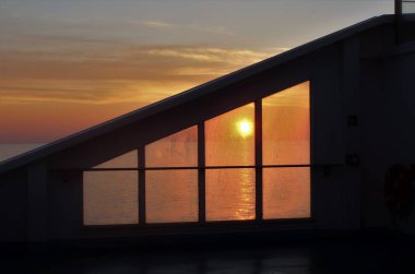 ufukta yükselen güneş ile bir yolcu gemisinden deniz üzerinde bir gündoğumu çağrıştıran görüntü