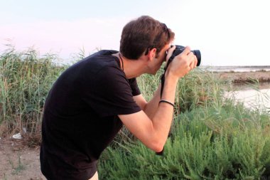 deniz de gün batımında onun kamera ile fotoğraf çekerken genç adam çağrıştıran hayal