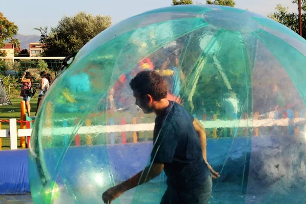 Havuzda yüzen şişme topun içinde eğlenen çocuk görüntüsü.