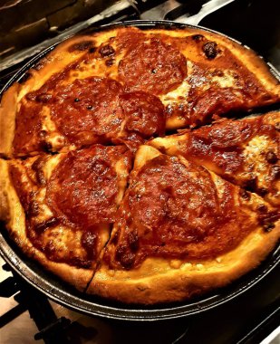 Baharatlı salam, domates ve mozzarella ile ev yapımı pizzanın canlandırıcı görüntüsü