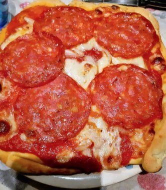 Baharatlı salam, domates ve mozzarella ile ev yapımı pizzanın canlandırıcı görüntüsü