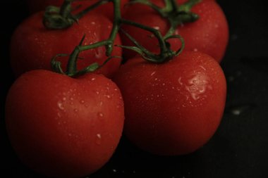 Siyah arkaplanda kırmızı, taze ve organik domatesler.