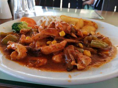 Tavuk, pirinç ve salata servis tabağında.