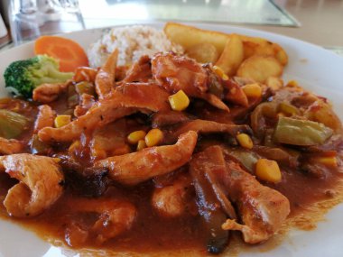 Tavuk, pirinç ve salata servis tabağında.