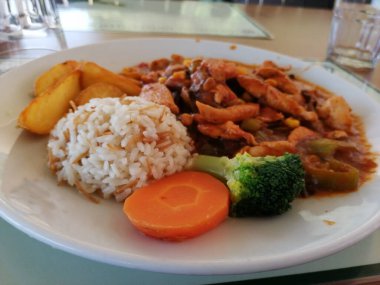 Tavuk, pirinç ve salata servis tabağında.