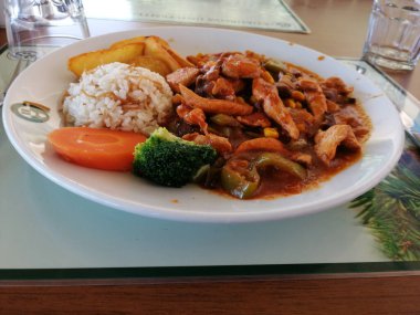 Tavuk, pirinç ve salata servis tabağında.