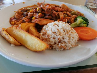 Tavuk, pirinç ve salata servis tabağında.