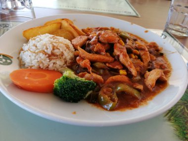 Tavuk, pirinç ve salata servis tabağında.