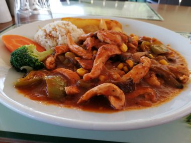 Tavuk, pirinç ve salata servis tabağında.