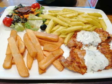 Tavuk, pirinç ve salata servis tabağında.