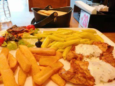 Tavuk, pirinç ve salata servis tabağında.