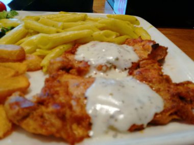 Tavuk, pirinç ve salata servis tabağında.