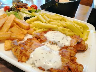 Tavuk, pirinç ve salata servis tabağında.