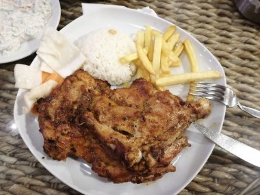 Tavuk, pirinç ve salata servis tabağında.