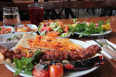 Tabakta lezzetli Adana kebapları ve salatalar