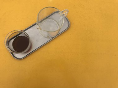 şeffaf cam fincan filtre kahve ve kolu cam konteyner kabı ile sarı tablo ve kopya alanı sağ tarafında çerçeve alüminyum gövde