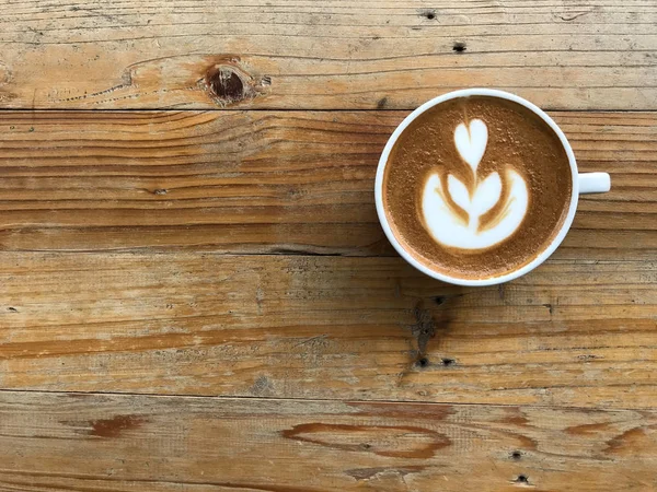 Secangkir kopi cappuccino panas dengan seni latte yang indah di meja kayu — Stok Foto