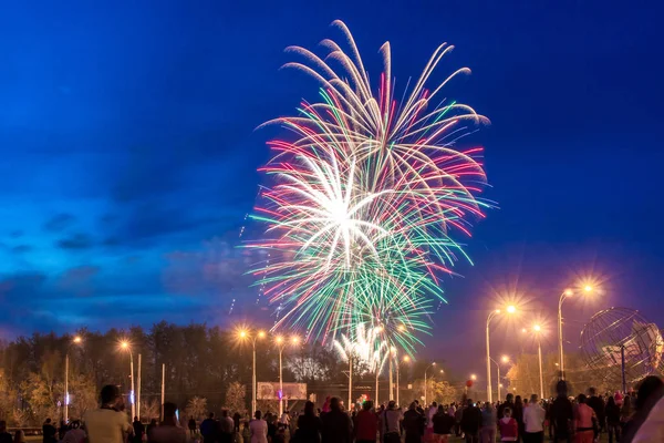 red, yellow and green fireworks lights in the dark blue sky above the city