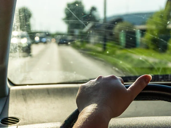 Müde Frauenhand ohne Maniküre am Lenkrad, Auto mit schmutzigem Glas fährt in Vorstädten, selektiver Fokus — Stockfoto