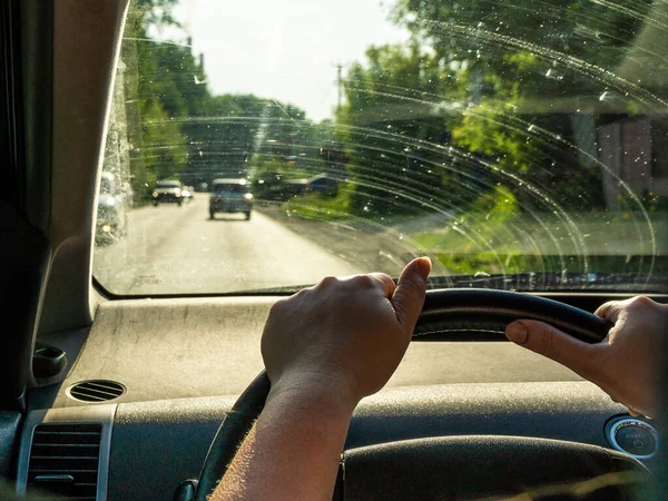 Hand einer Frau mittleren Alters am Lenkrad, hinter einer schmutzigen Windschutzscheibe, der Dorfrand, selektiver Fokus — Stockfoto