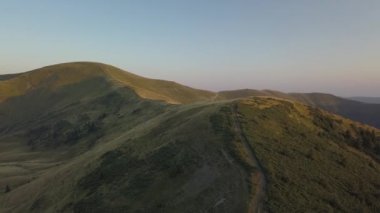 Drone kadar gider ve kamera aşağı dağ sırtı günbatımı sırasında bir sırt tarafında aydınlatma güzel renklerle doğru yatırır. Konumu Karpat Dağları