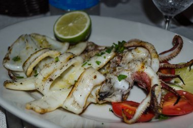 Domates ve limon ile Sicilya Restoran Izgara kalamar, yakın çekim. Akdeniz mutfağı - ızgara deniz ürünleri.
